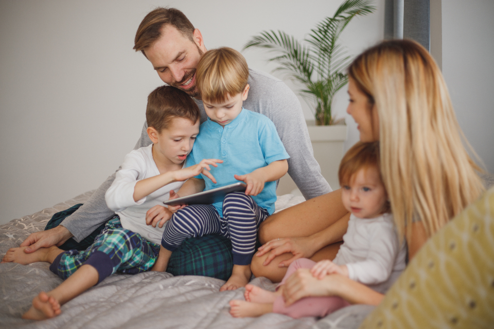 Mamma, papà e bambini che giocano insieme sul divano di casa