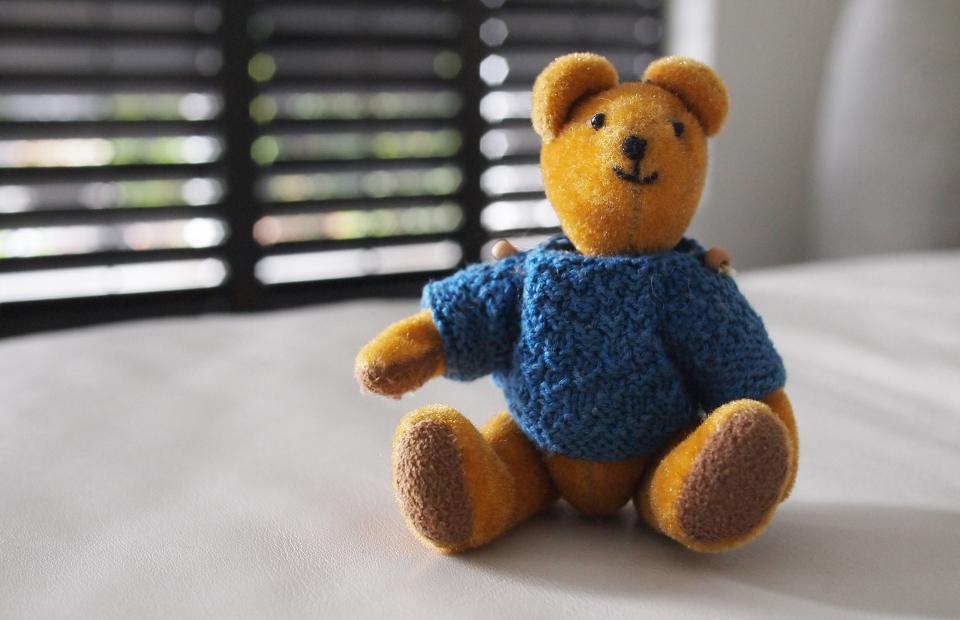 Vecchio orsacchiotto di peluche seduto su un pavimento di legno: i giocattoli consumati dal tempo che non si buttano