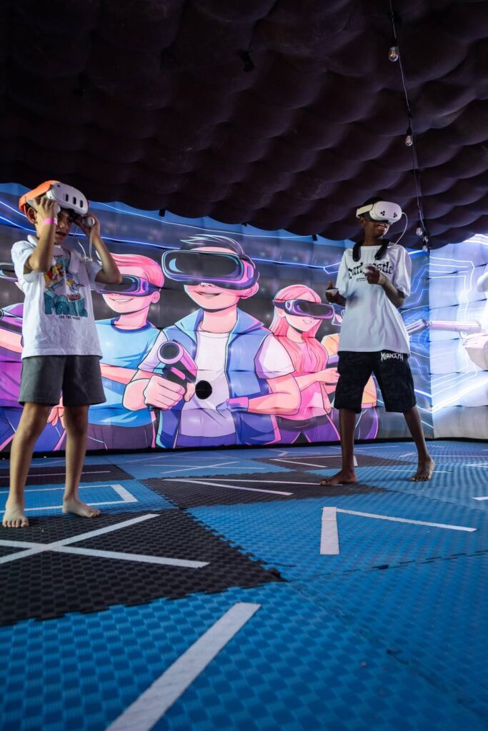 Due bambini con i visori per la realtà virtuale dentro un gonfiabile con la parete decorata