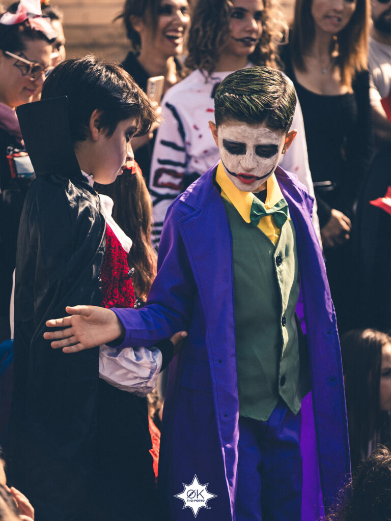 Due bambini in costume da cattivo: uno con mantello nero e colletto alto, l'altro con cappotto viola e trucco bianco