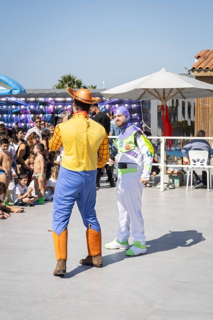 Woody di spalle e Buzz Lightyear di fronte, sul palco davanti ai bambini seduti