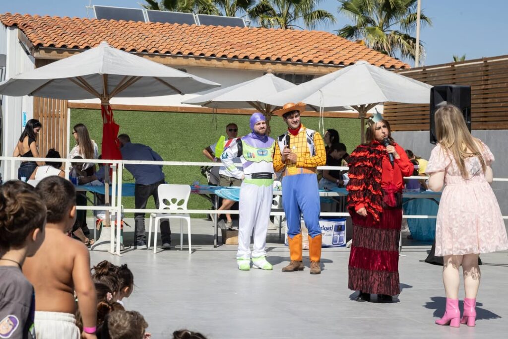 Woody e Buzz Lightyear in costume sul palco, con una presentatrice in abito rosso e una bambina in abito rosa